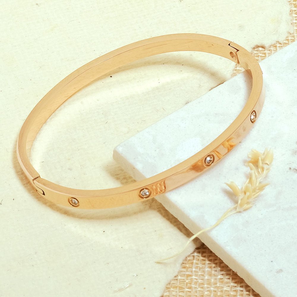 Elegant stainless steel bangle with a sleek push-lock design and polished finish, available in gold, rose gold, and silver, perfect for everyday wear, effortless stacking, and styling with watches.
