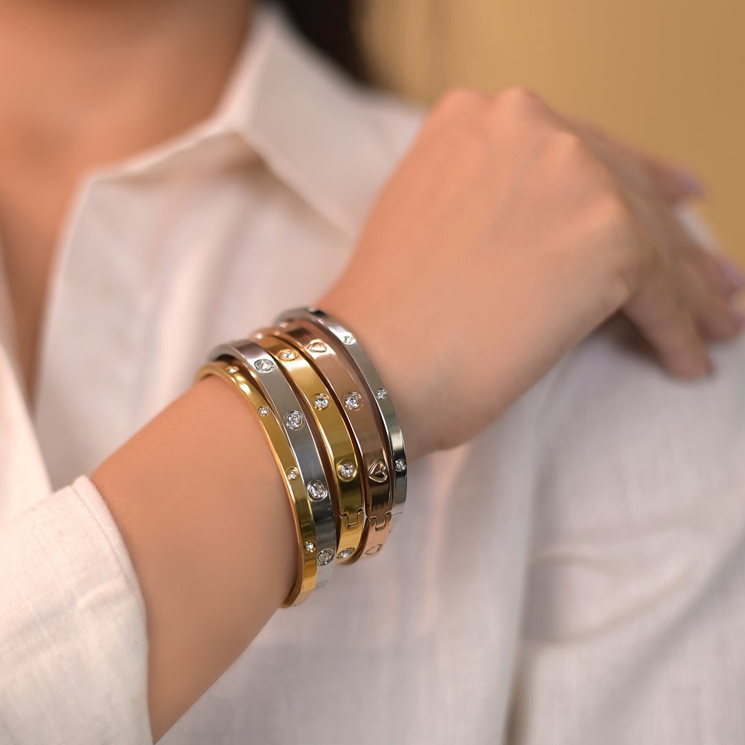 Elegant stainless steel bangle with a sleek push-lock design and polished finish, available in gold, rose gold, and silver, perfect for everyday wear, effortless stacking, and styling with watches.