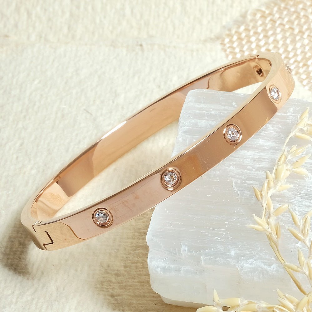 Elegant stainless steel bangle with a sleek push-lock design and polished finish, available in gold, rose gold, and silver, perfect for everyday wear, effortless stacking, and styling with watches.